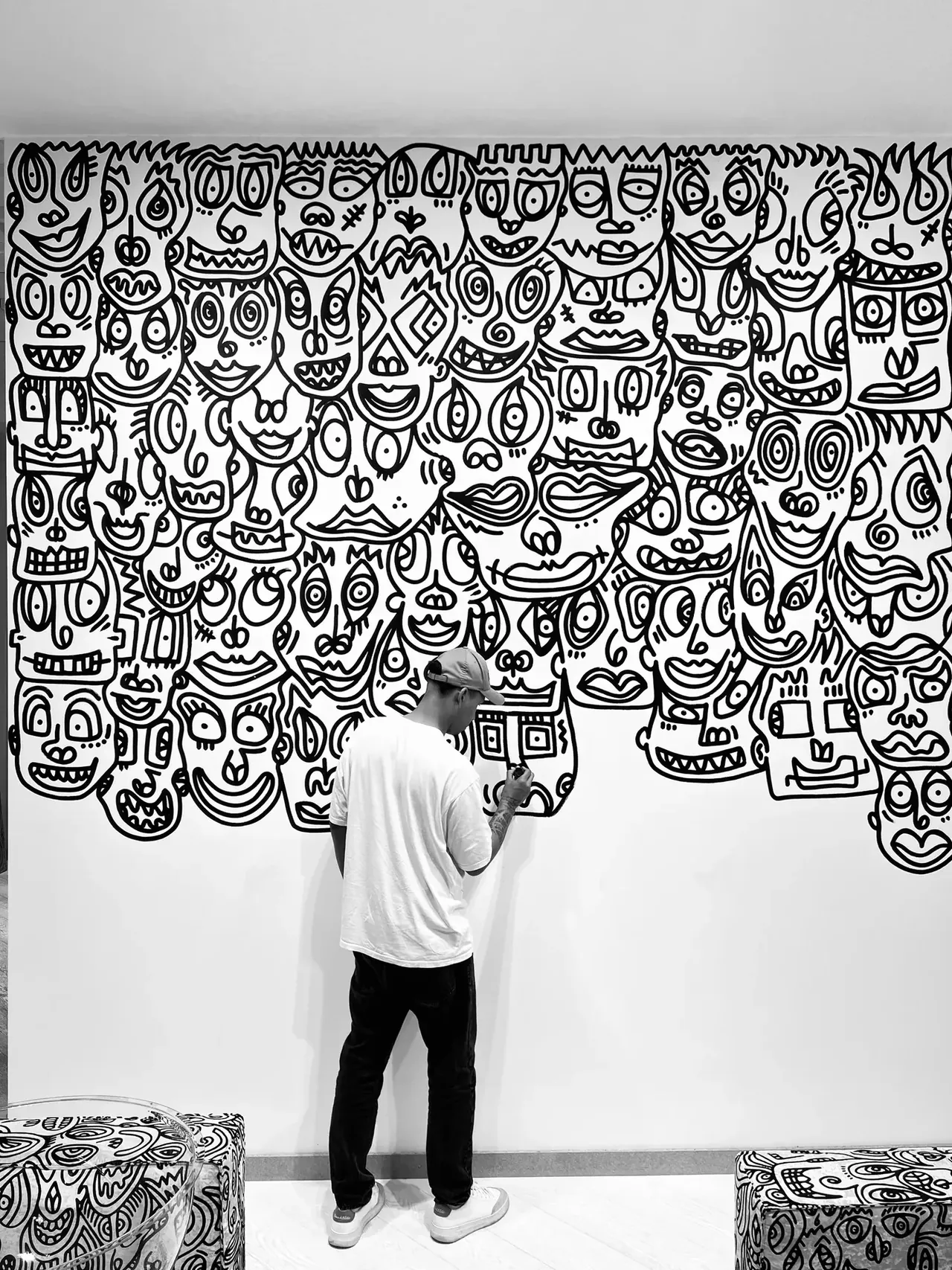 Romulo Kuranyi drawing a wall of faces in black marker